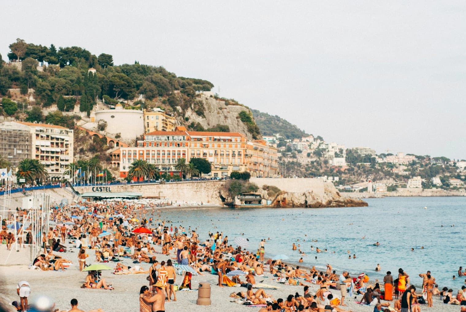 Parking bondé en bord de mer en été avec des voitures qui attendent, vue sur une plage méditerranéenne ensoleillée